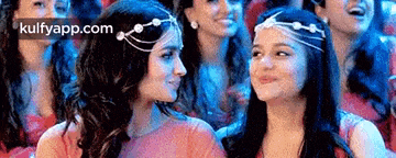 a group of women are sitting next to each other in a crowd and smiling .