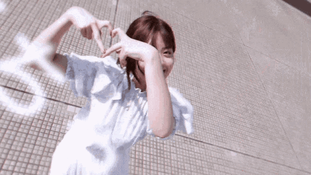 a woman in a white dress is smiling and pointing at something