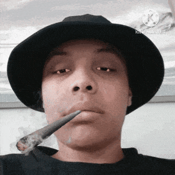a man wearing a black hat is smoking a cigarette in his mouth