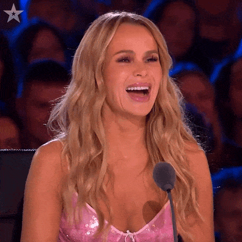 a woman in a pink dress is laughing while speaking into a microphone