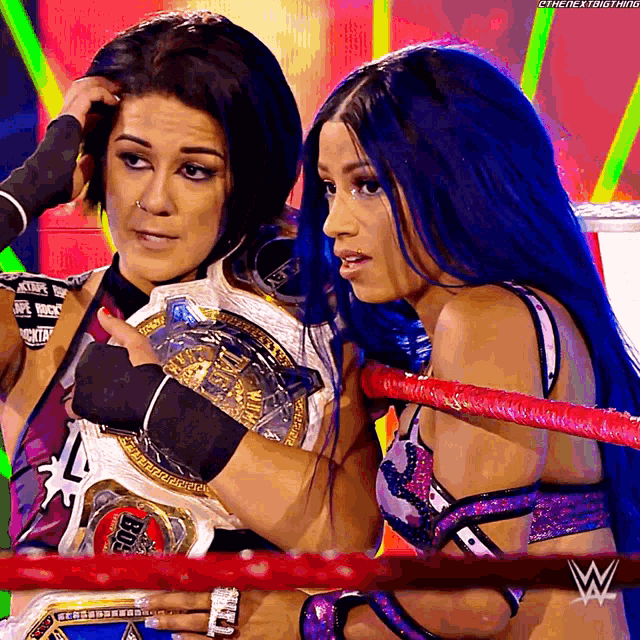 two women in a wrestling ring with one holding a wrestling belt that says big
