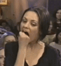 a woman is sitting in a crowd with her hand on her mouth .