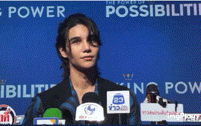 a man stands in front of microphones in front of a blue wall that says king power