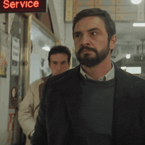 a man with a beard stands in front of a sign that says service