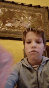 a young boy is taking a selfie in front of a picture on a wall .