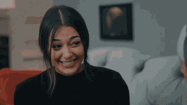 a woman in a black turtleneck is smiling