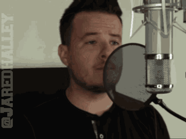 a man singing into a microphone with the words @scaredhalliey visible behind him