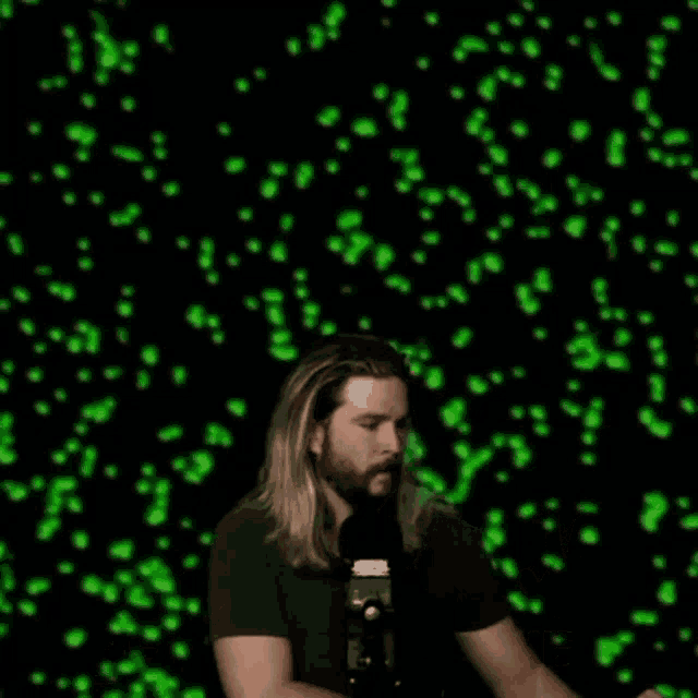a man with long hair and a beard is standing in front of a green background and says they 're everywhere