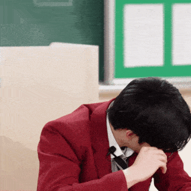 a man in a red suit and tie is covering his face