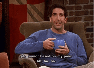 a man is sitting in a chair holding a blue cup and saying " ah humor based on my pain "