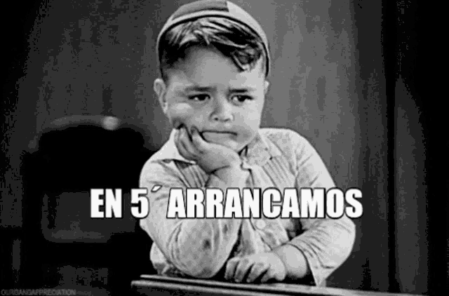 a little boy is sitting at a desk with his hand on his chin and a caption that says en 5 arrancamos .
