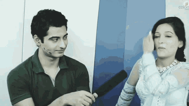 a man and a woman are sitting in front of a wall that has the word colors on it