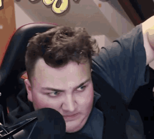 a man is sitting in a chair in front of a microphone and looking at the camera .