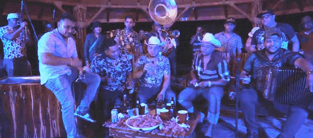 a group of men sitting around a table with bottles of beer