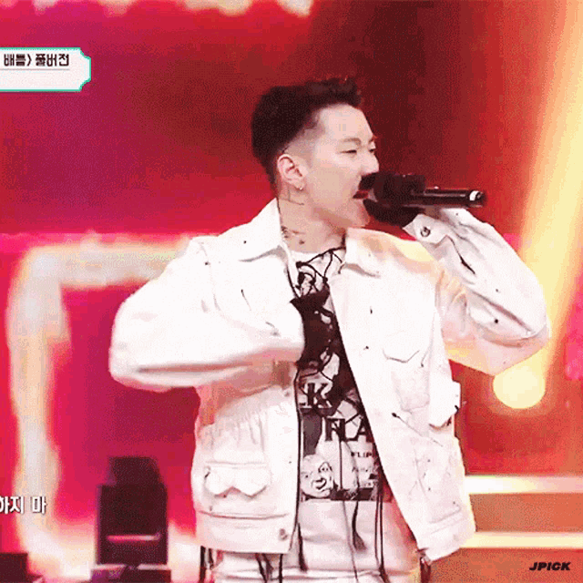 a man in a white jacket singing into a microphone with jpick written on the bottom right