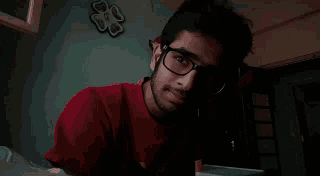 a young man wearing glasses and a red shirt