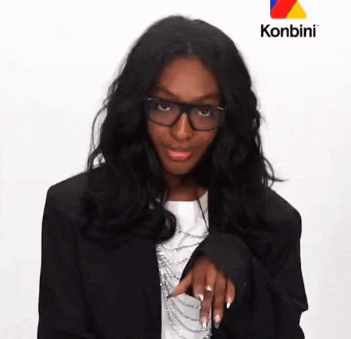a woman wearing glasses and a black jacket is standing in front of a sign that says konbini .
