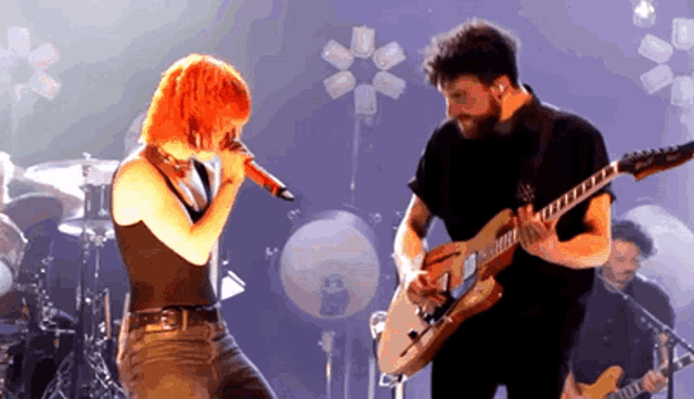 a man playing a guitar and a woman singing into a microphone