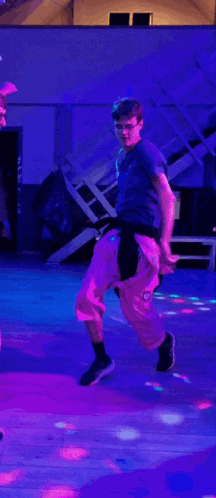 a group of people are dancing in a room with purple lights .