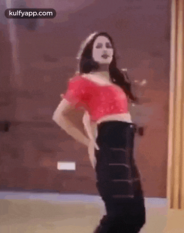 a woman in a red top and black pants is dancing .