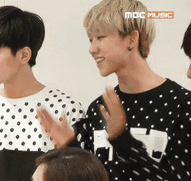 a man wearing a black and white polka dot shirt is clapping his hands