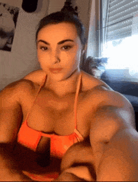 a woman with very large muscles is taking a selfie in front of a window