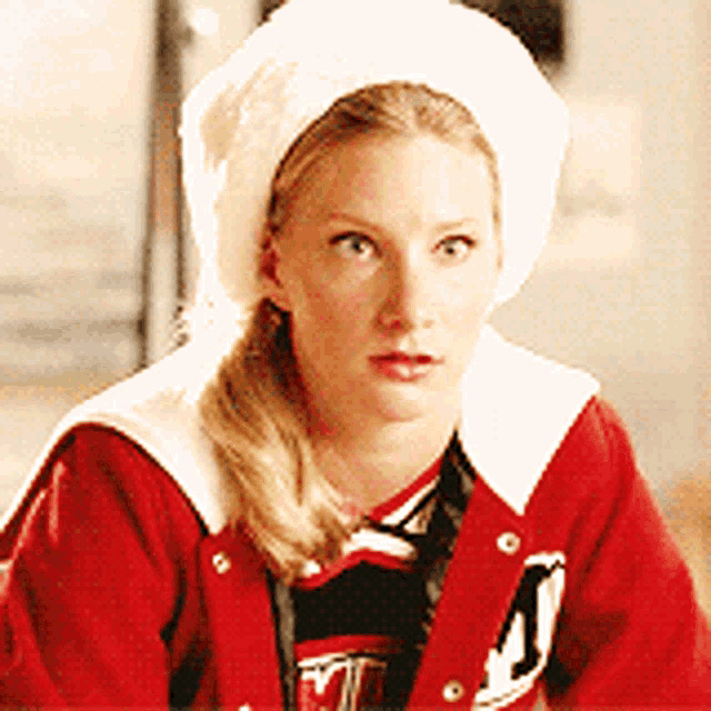 a woman wearing a red jacket and a white hat has the letter j on her shirt