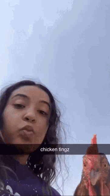 a girl taking a selfie with a chicken and the caption chicken tingz