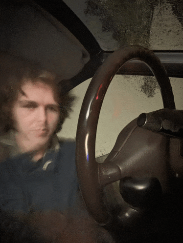 a blurry picture of a man behind the steering wheel of a car