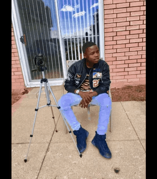 a young man sitting in a chair with a camera on a tripod