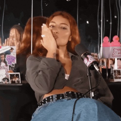 a woman blowing a kiss in front of a microphone that says ' mrs. shark '