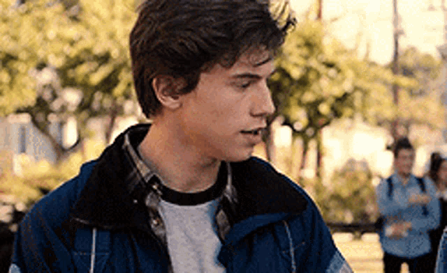 a young man wearing a blue jacket and a plaid shirt .