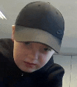 a young boy wearing a baseball cap and a black shirt .