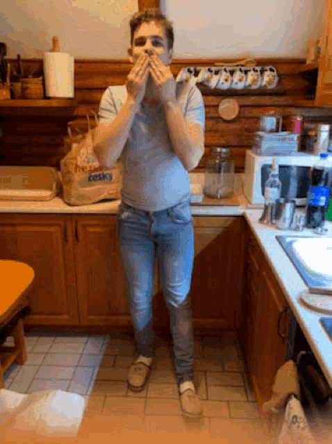 a man standing in a kitchen with a bag that says desky on it
