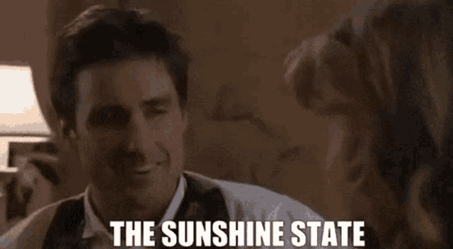 a man in a suit and tie is smiling while talking to a woman and the words the sunshine state are visible