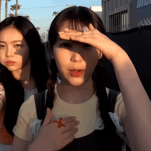 a girl covering her face with her hand while another girl looks at her