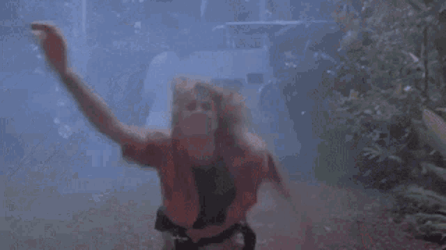 a woman is sitting in front of a chain link fence with her hands in the air .