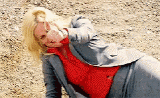 a woman wearing a red sweater and a grey jacket is laying on the ground