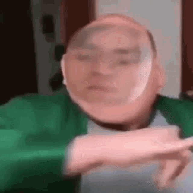 a man in a green jacket is making a funny face with his face covered in a balloon .