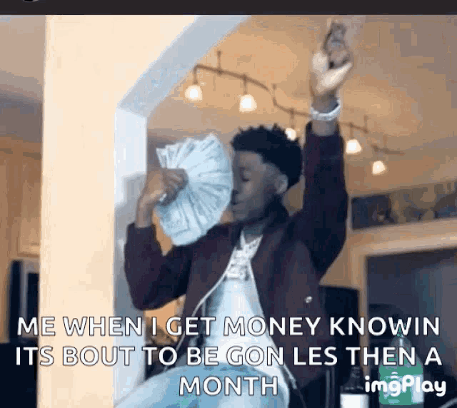 a man is holding a fan of money in his hand and says me when i get money