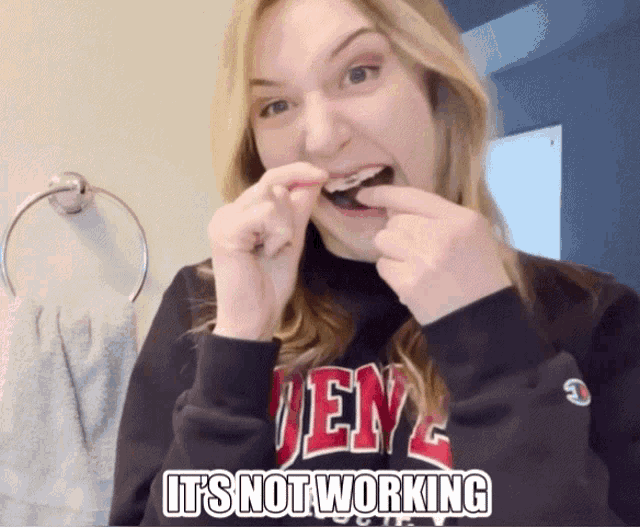 a woman wearing a sweatshirt that says ' jen ' on it is brushing her teeth