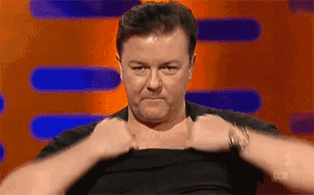 a man in a black shirt is taking off his shirt .