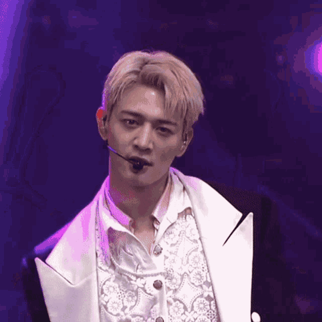 a man with a microphone in his mouth is wearing a white shirt and a black jacket