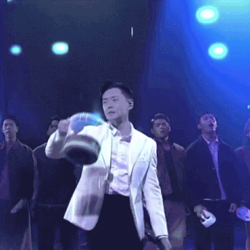 a man in a white suit and bow tie is holding a bucket in his right hand