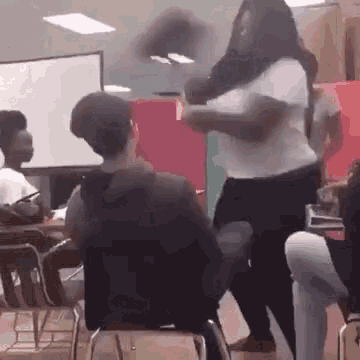 a group of people are sitting in chairs in a classroom and a woman is standing in front of them .