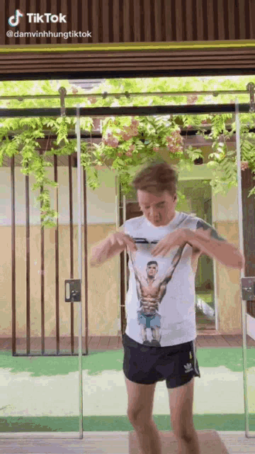 a man wearing a shirt with a picture of a man on it is standing in front of a glass door