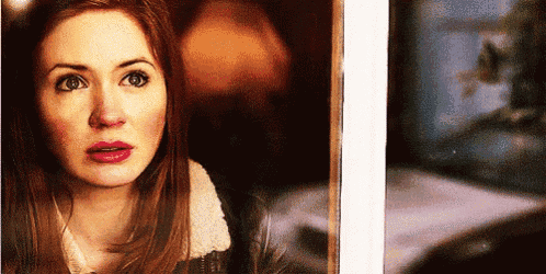 a woman is looking out a window with a surprised look on her face