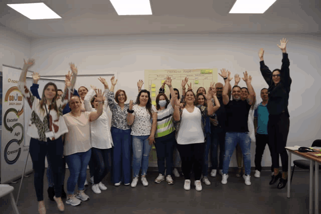 a group of people are posing for a picture with their hands in the air in front of a board that says o novo