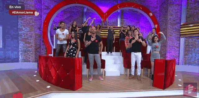 a group of people are standing in front of a heart shaped stage with the words en vivo on the bottom