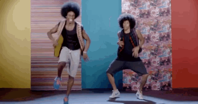a couple of men are dancing in front of a wall